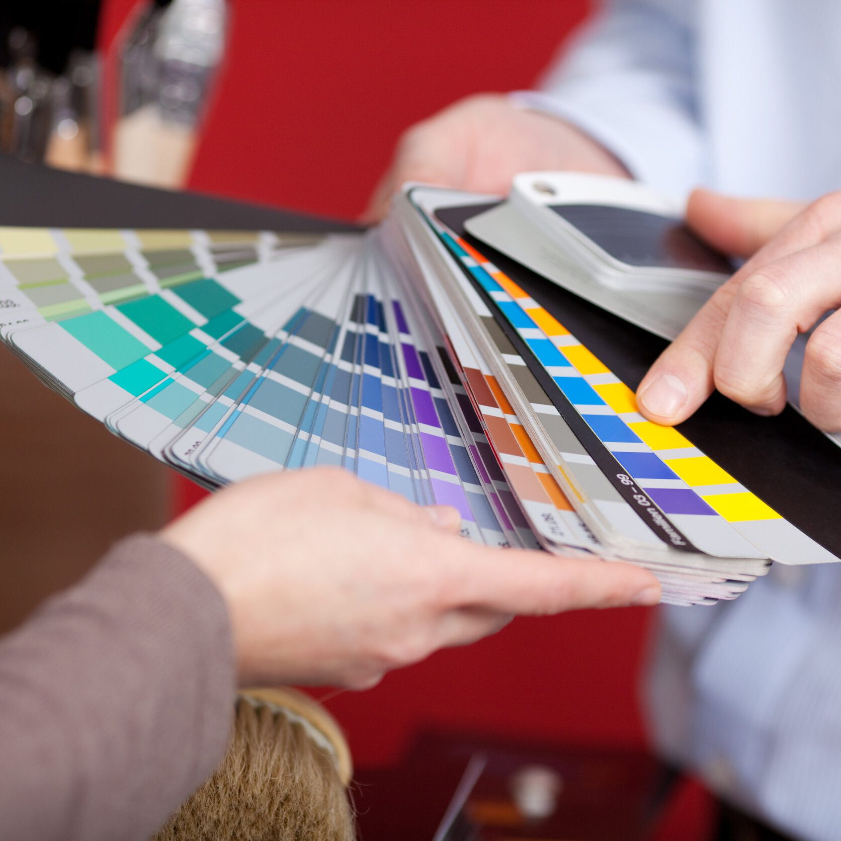 Interior decorator in a meeting with a client discussing various paint colours from a colourful set of swatches he is holding in his hand